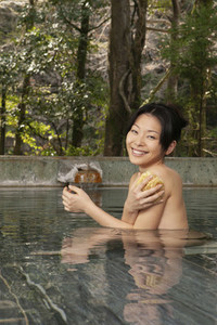 Portrait happy young woman with loofah in pool at Onsen