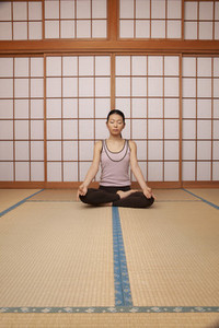 Serene young woman meditating in lotus pose on mat