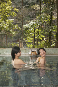 Young woman with loofah scrubbing friend039s back in pool at Onsen