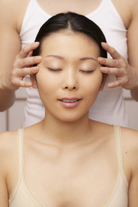 Serene young woman receiving scalp massage at spa
