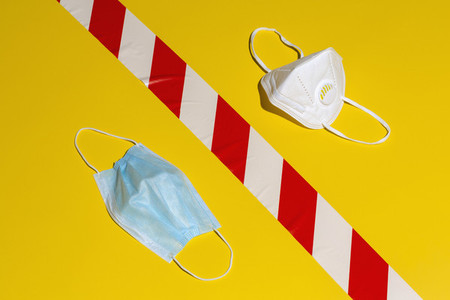Surgical and N95 face masks on yellow background with warning tape