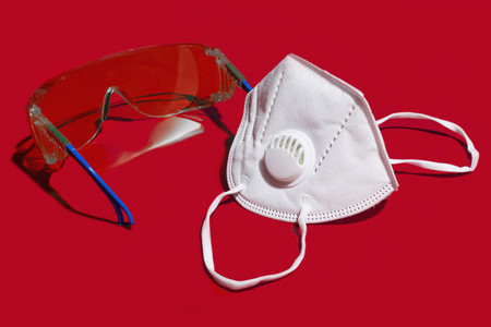 Close up N95 face mask and protective goggles on red background