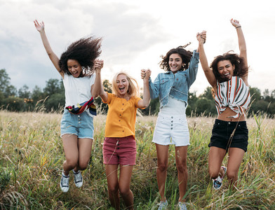 Group of diverse women jumping together outdoors  Friends having fun during vacation