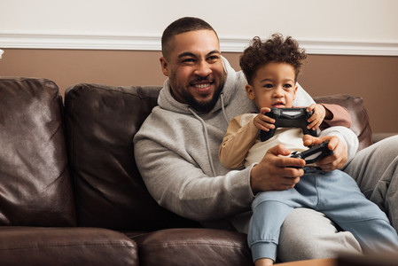 Excited father and son playing video game on a console at home