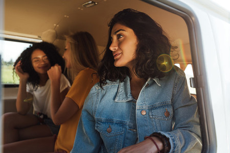 Three women sitting together in van during road trip