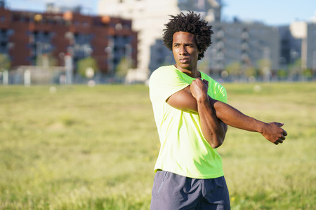 Black man with afro hair doing stretching after running outdoors