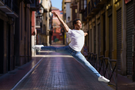 Black athletic man doing an acrobatic jump outdoors
