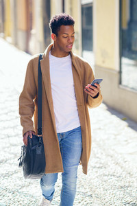 Young black man walking down the street carrying a briefcase and a smartphone