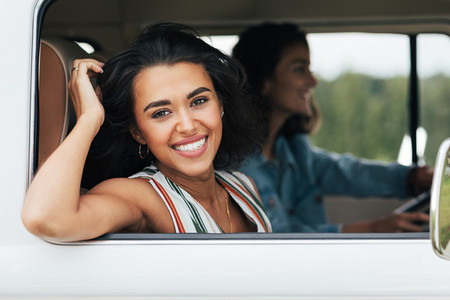 Happy woman sitting on a passenger seat in minivan and looking at camera