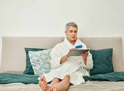Senior woman with grey hair making an online purchase from bedroom