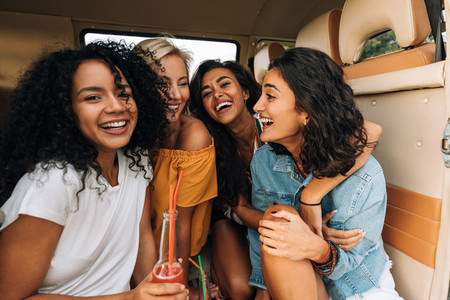 Multi ethnic group of young women laughing while sitting in a minivan
