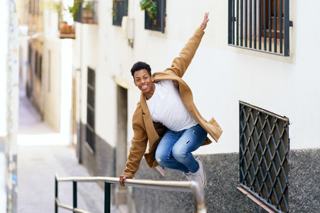 Cuban man jumping for joy over a handrail in the street