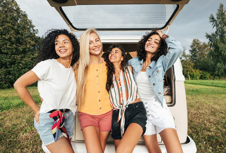 Group of four multi ethnic women standing near a minivan