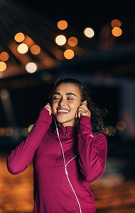 Female runner listening to music on earphones at night