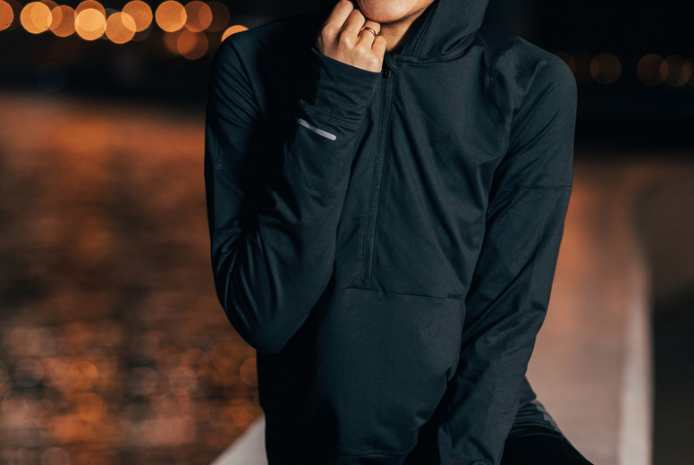 Beautiful middle east woman in hooded shirt sitting outdoors at night relaxing during a workout