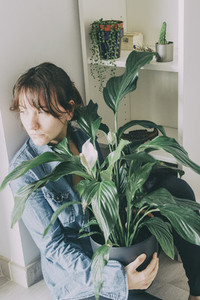 portrait of a woman sits on the floor and hugs a plant