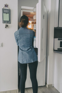 girl inside the kitchen opening the fridge door