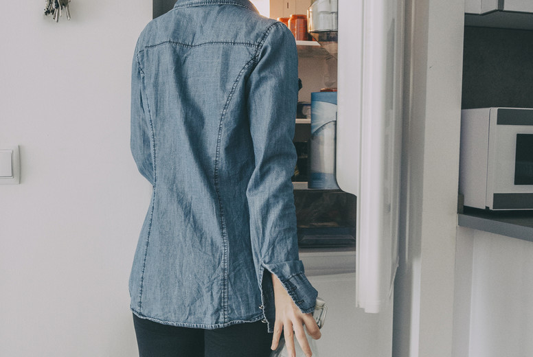 girl inside the kitchen opening the fridge door and looking inside while