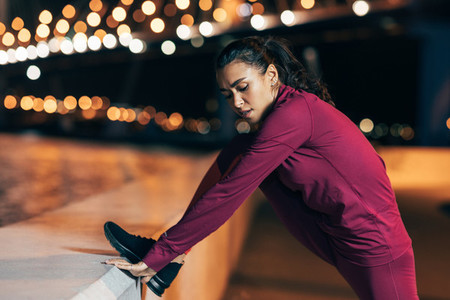 Fit woman stretching her body during a workout at night
