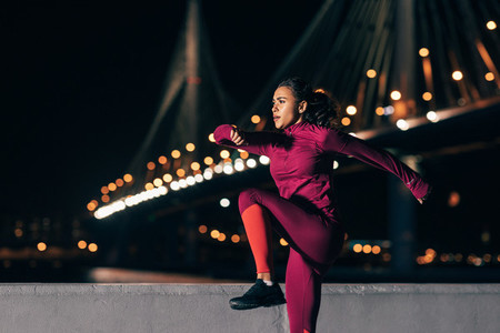 Fit woman doing warming up exercises at night outdoors