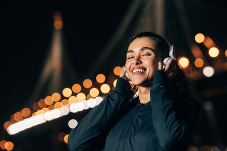 Happy woman wearing white wireless headphones listening to music with closed eyes