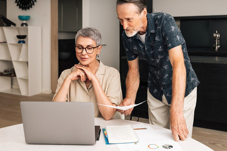 Senior caucasian couple calculating bills at home  Two mature people looking at laptop and managing finances
