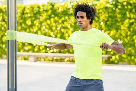 Black man working out with elastic band outdoors