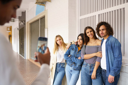 Multi ethnic group of friends taking photos with a smartphone in the street