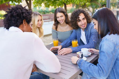 Multi ethnic group of friends having a drink together in an outdoor bar