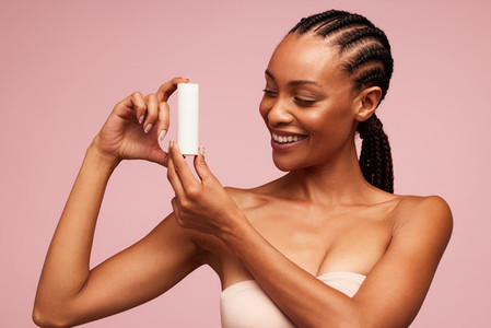 Happy african woman holding a cosmetic product