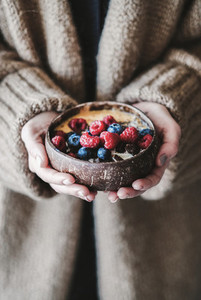 Healthy vegan breakfast bowl with oats in womans hands