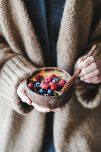 Healthy vegan breakfast bowl with oats  berries in womans hands