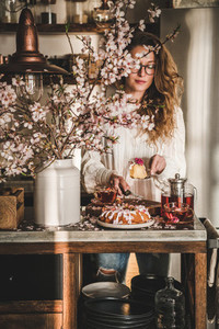 Woman serving homemade gluten free bundt cake near blooming branches