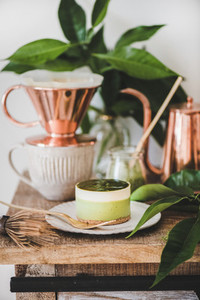Green matcha cheesecake and coffee in copper pot and mug