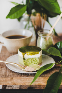 Green matcha cheesecake and coffee in mug on kitchen counter