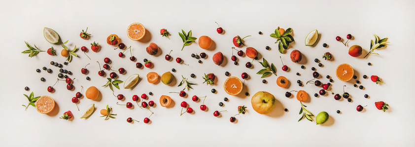 Flat lay of various summer fruits and berries over white background