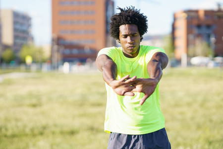 Black man with afro hair doing stretching after running outdoors