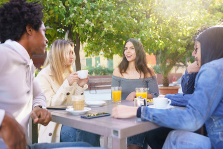 Multi ethnic group of students having a drink on the terrace of a street bar