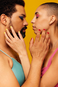 Closeup of queer male and bald woman facing each other