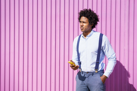 Black man with afro hairstyle carrying a sports bag and smartphone in yellow background