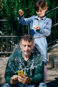 Girl blowing up a water filled balloon over her fathers head