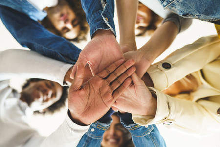 Hands of a multi ethnic group of friends joined together as a sign of support and teamwork