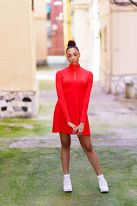 Young black woman in red dress posing on a street with colorful walls