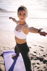 Young yogi woman practicing yoga on beach