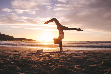 Fitness female practicing yoga at sunset
