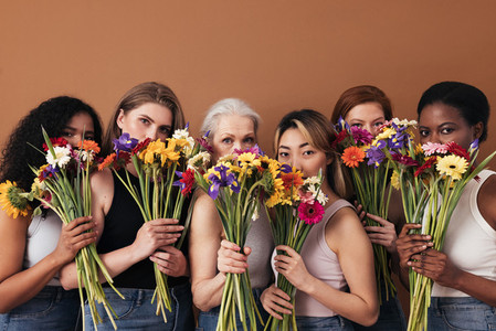 Group of diverse women hide their faces by bouquets of flowers  Portrait of six females of a different race  age  and figure type