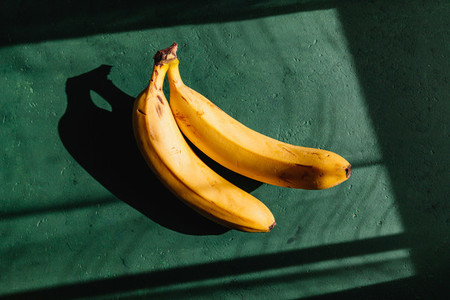 Bananas on a green background  Summer abstract creative photography with sun light and shadows