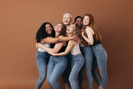 Six laughing women of a different race  age  and figure type  Group of multiracial females having fun against a brown background