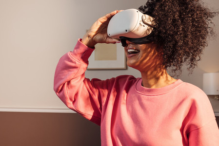 Cheerful woman in casuals standing indoors exploring virtual reality