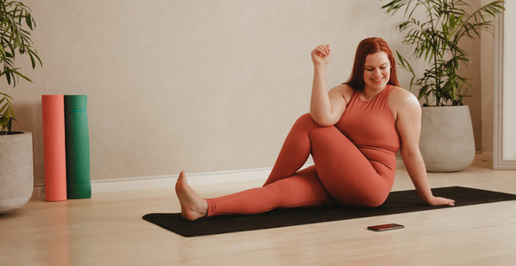 Woman following instruction on cellphone while doing yoga